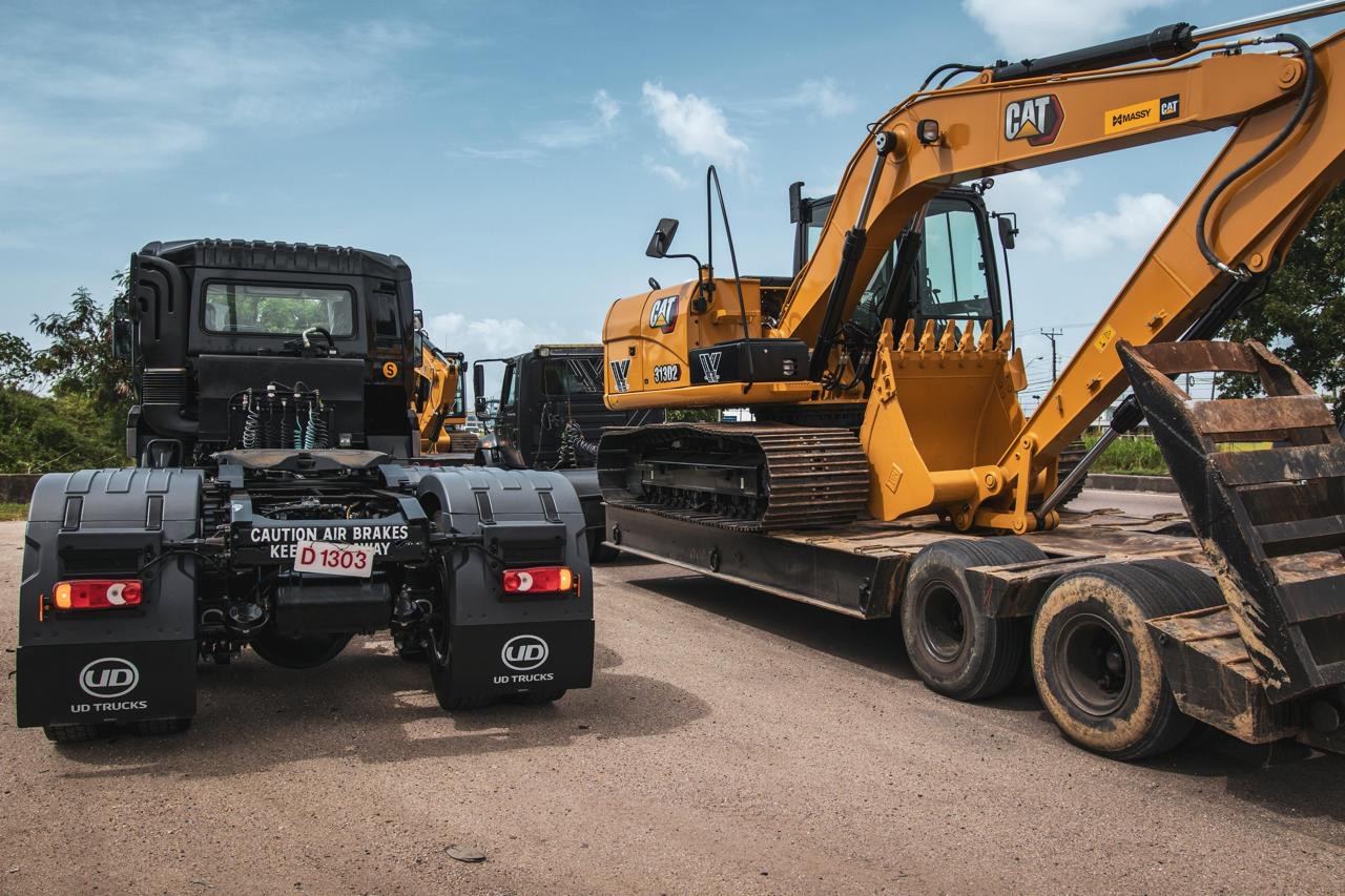 Cat 313 excavator loaded for transport behind a UD tractor
