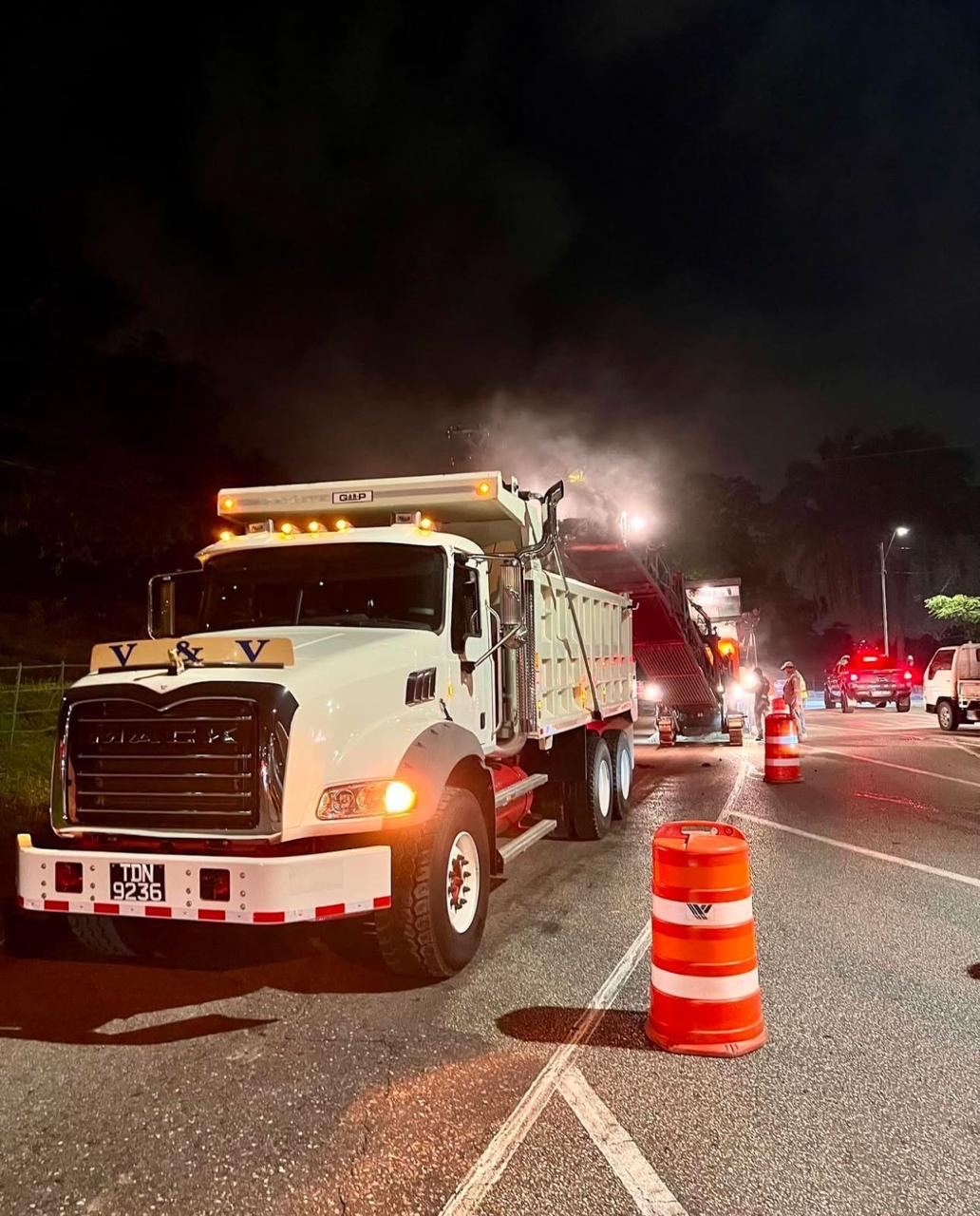 Mack tipper feeding an asphalt paver on a night road job